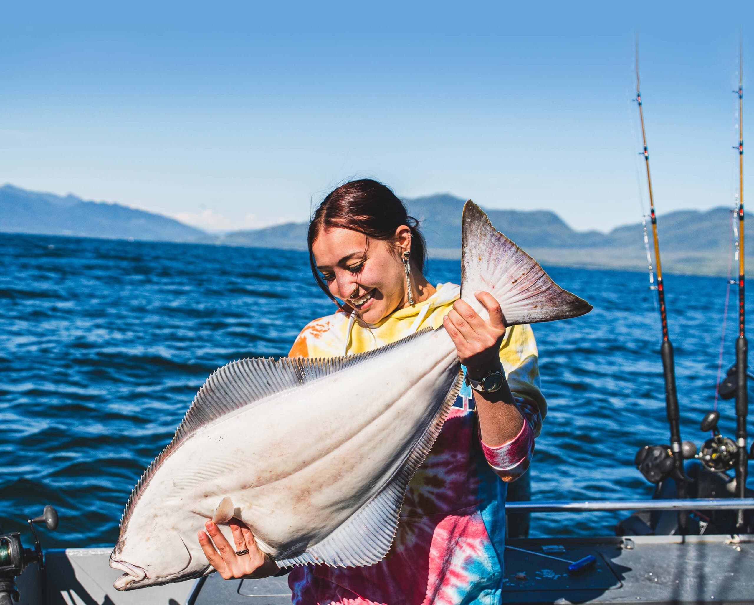 Angler holding a fresh Pacific halibut on a Juneau fishing charter boat